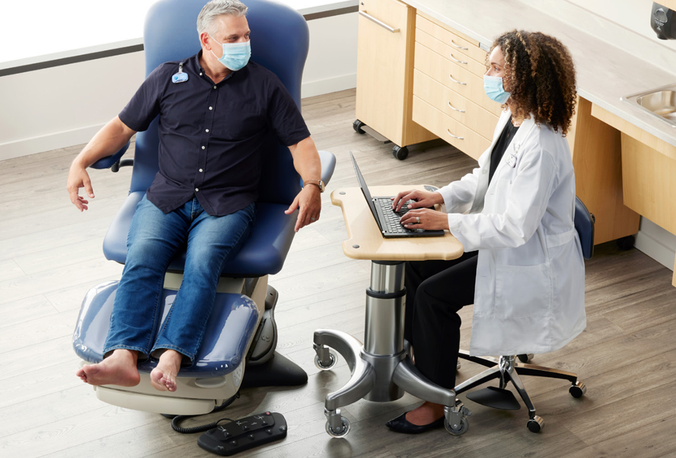 Patient in an exam chair speaking with a podiatrist.