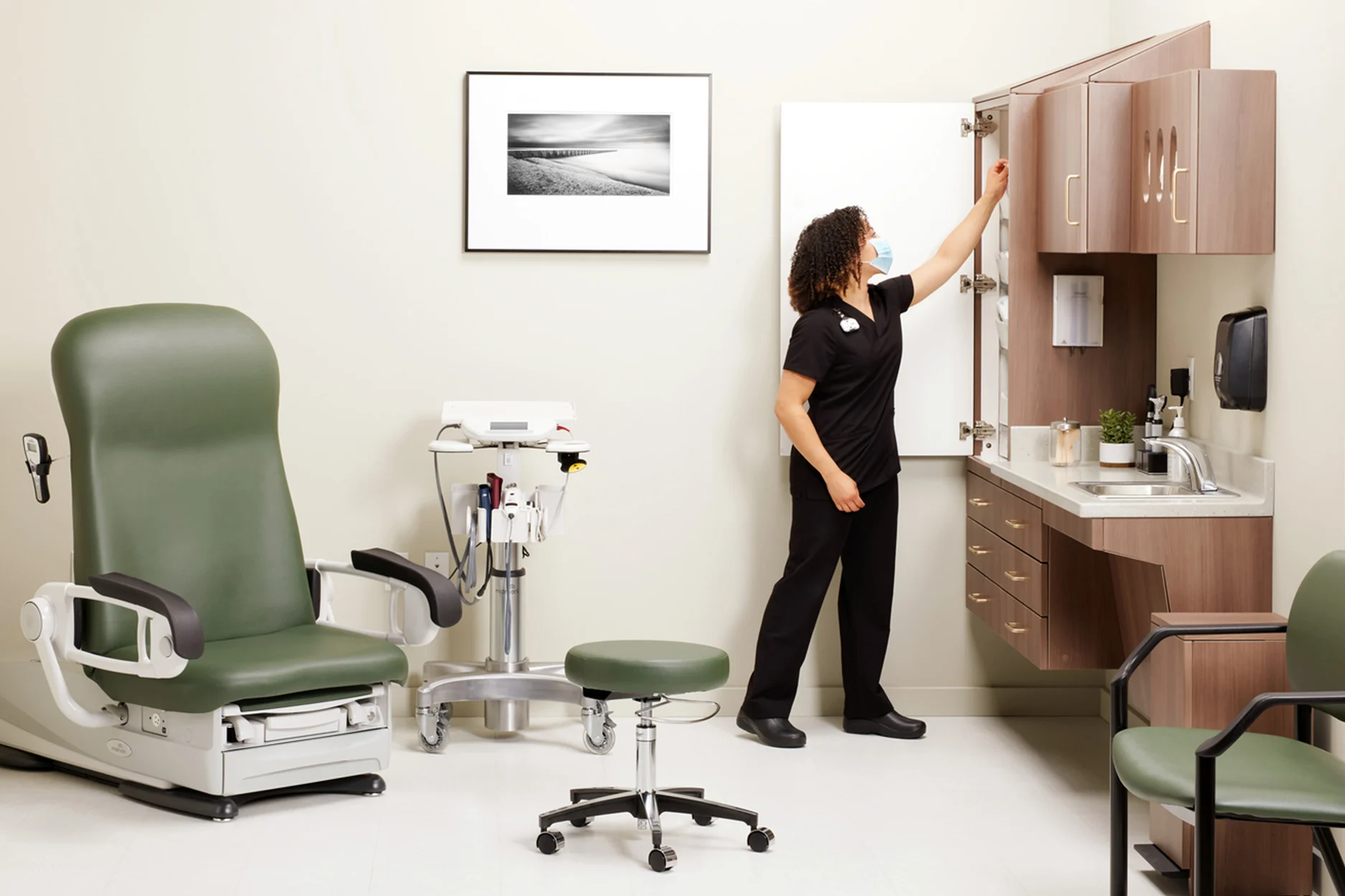 nurse accessing top shelf of cabinets in medical exam room