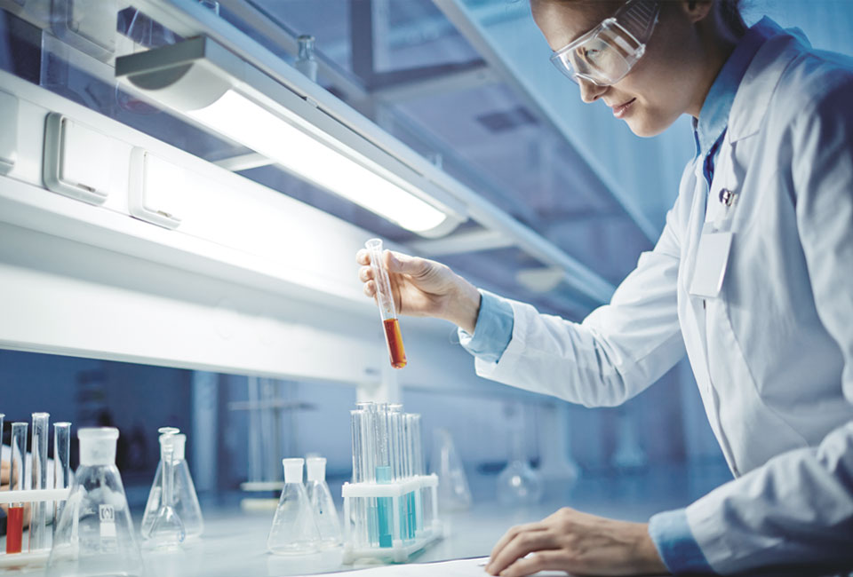 A medical professional in a lab environment with test tubes and glassware