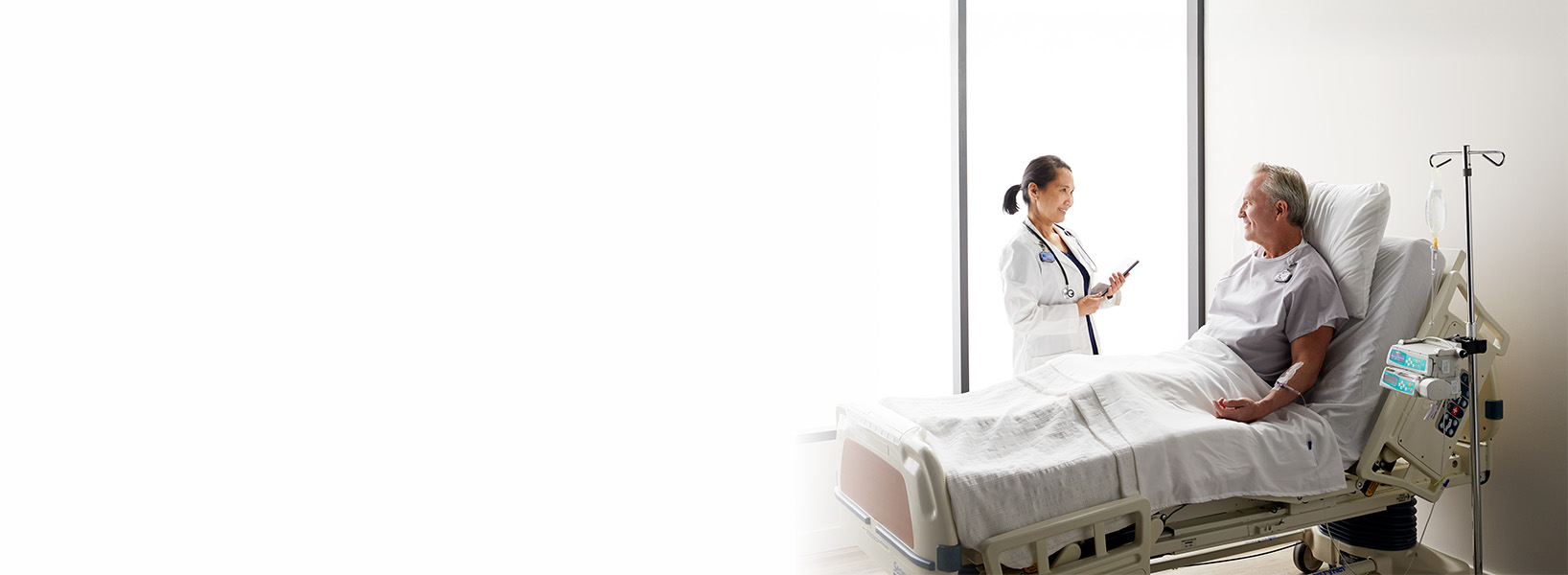 a doctor talking a patient who is laying in bed