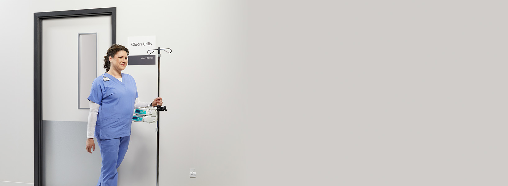 a nurse pushing an IV pump out of a utility room
