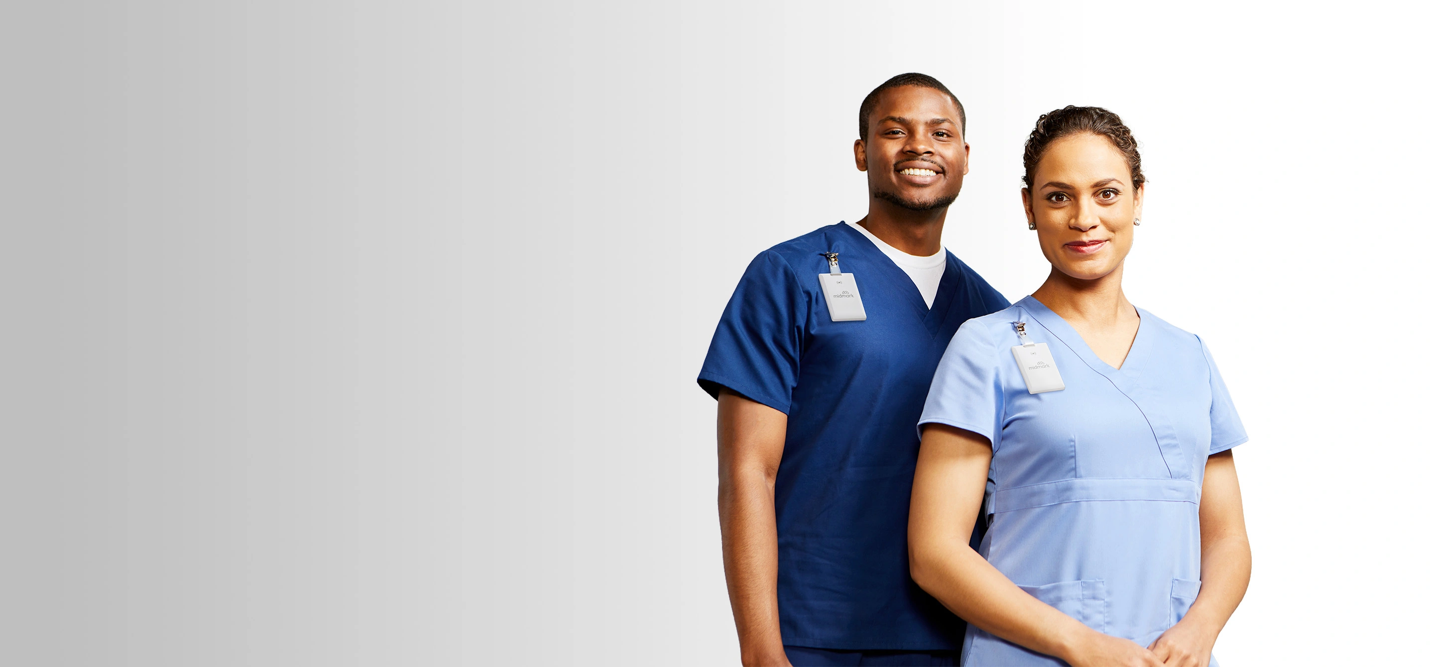 two nurses in blue scrubs wearing midmark rtls badges
