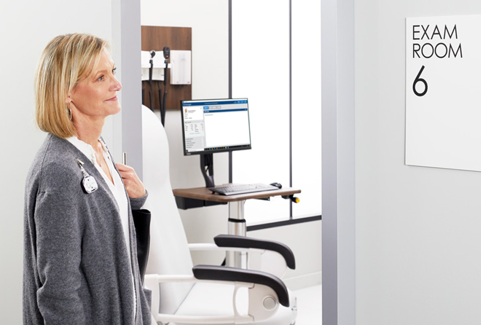 Patient approaching exam room looking at sign reading exam room 6