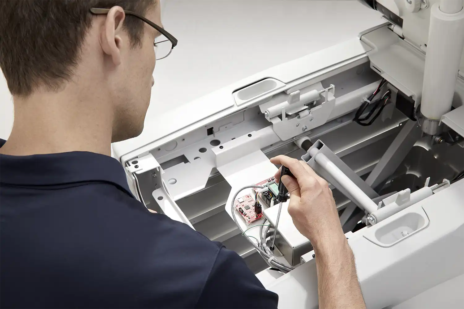 Man with navy shirt and glasses servicing Midmark machine