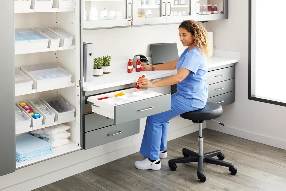 Pharmacy_Room_Vet_Tech_Seated_Reaching_Base_Cabinet_Left
