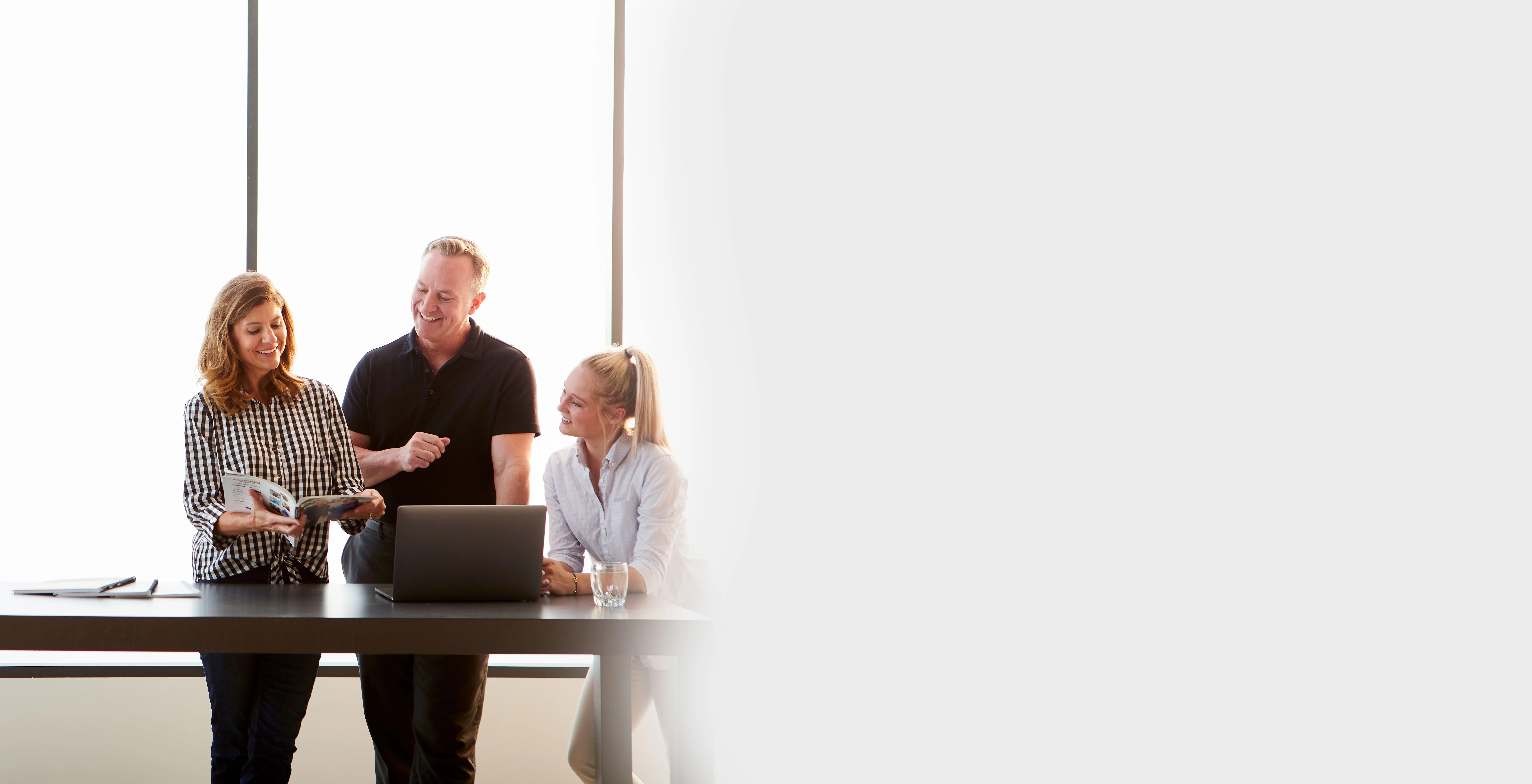 three midmark employees looking at a magazine and laptop