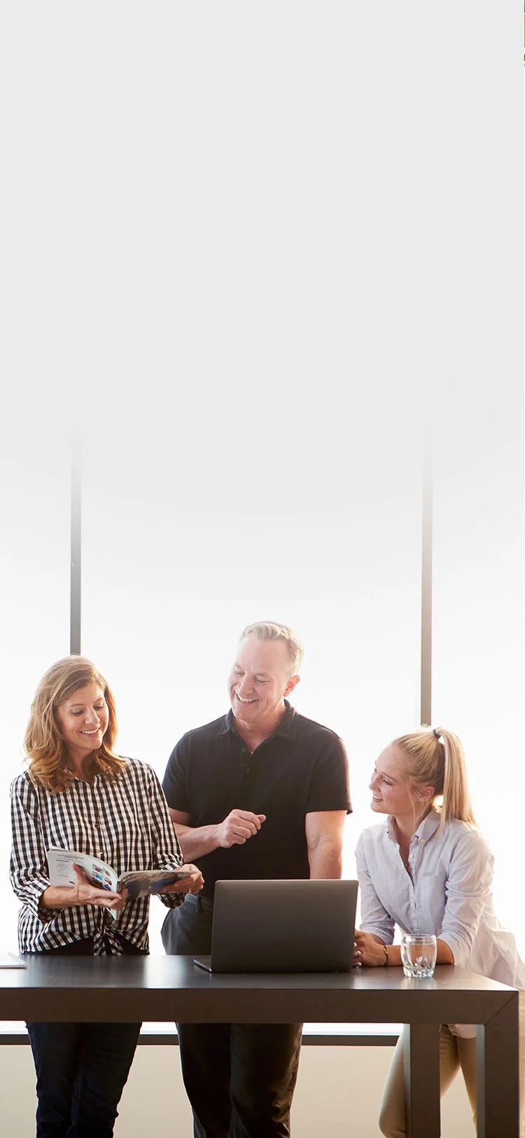 three midmark employees looking at a magazine and laptop
