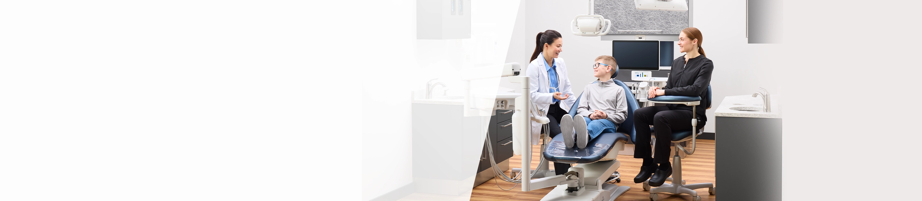 Young male patient speaking with dentist and dental assistant in operatory