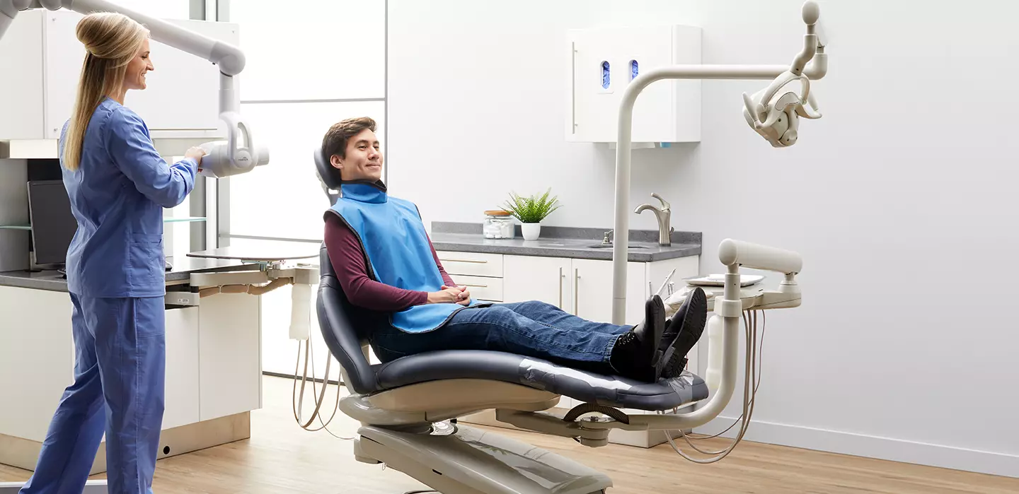 nurse moving dental camera to take picture of patient sitting in dentists chair