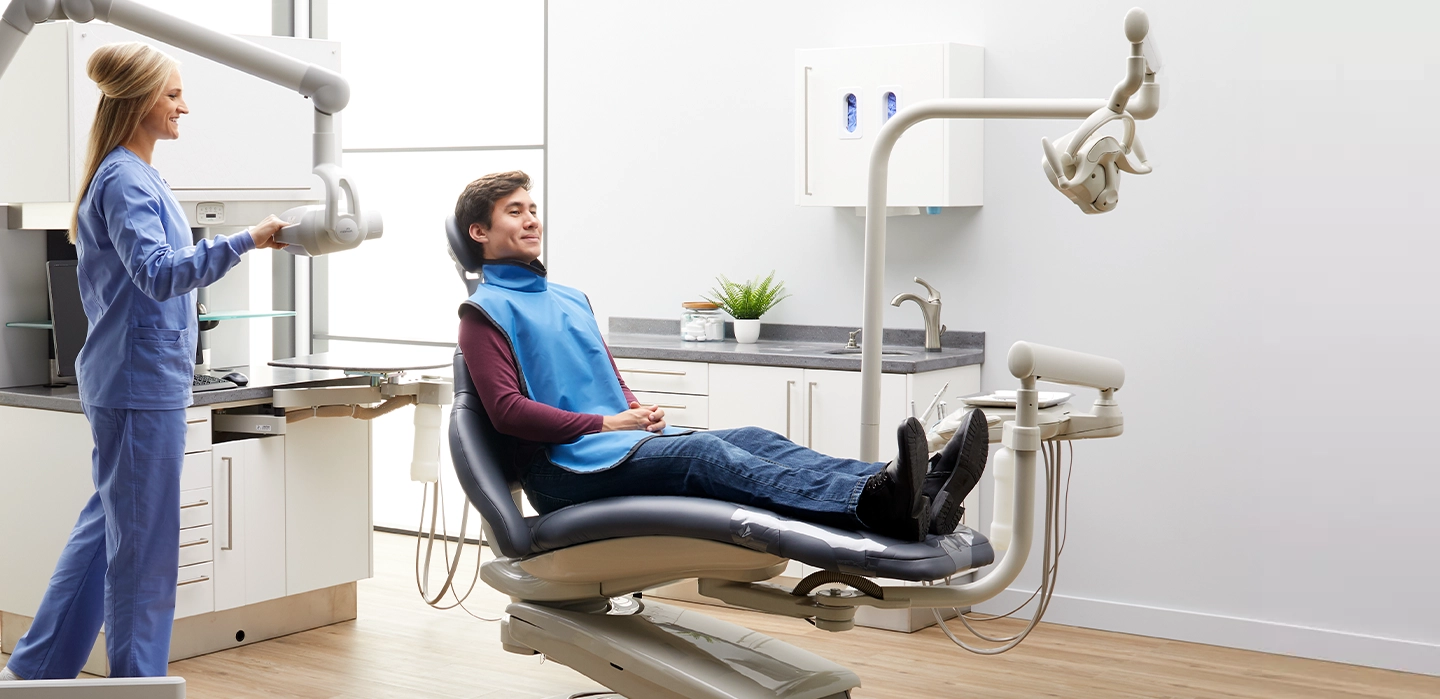 nurse moving dental camera to take picture of patient sitting in dentists chair