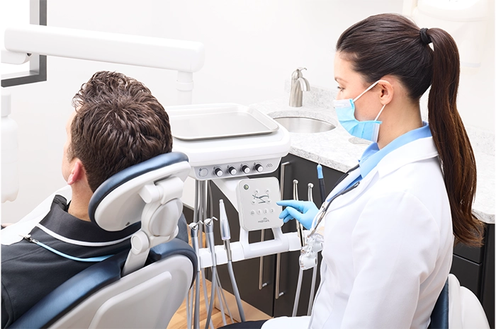 ProductPage-MidmarkDeliverySystem-img7-high-back-dentist-adult-patient-using-touchpad-handpieces-set