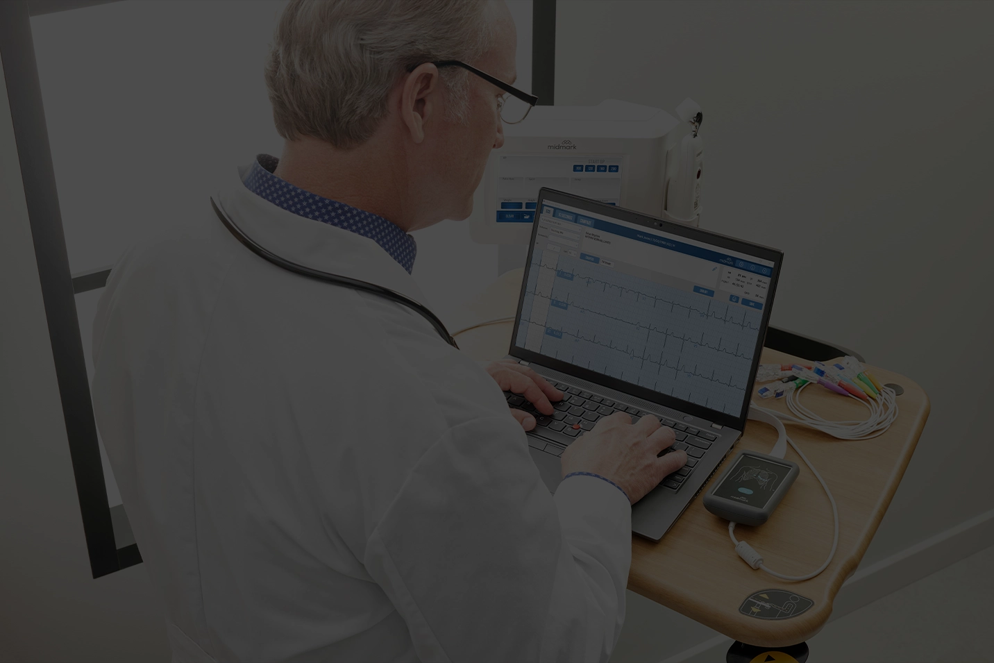 Doctor working on laptop with midmark diagnostic devices connected