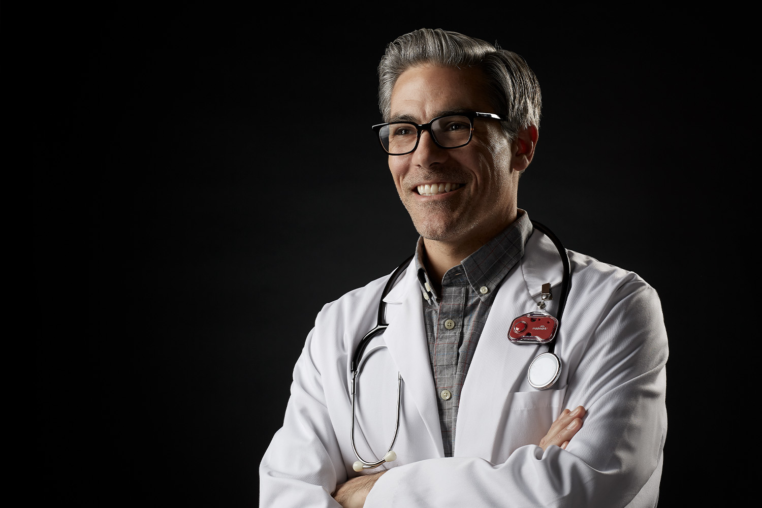 Doctor in a white coat with his arms crossed, smiling
